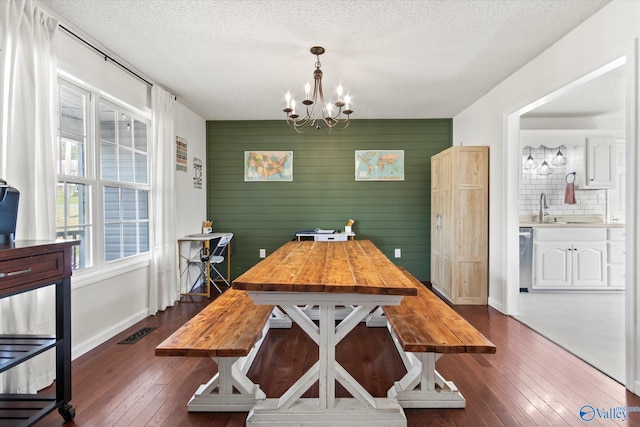 dining room with dark wood-style flooring, a notable chandelier, a textured ceiling, and visible vents