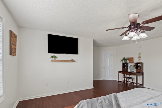 bedroom with a textured ceiling, baseboards, and wood finished floors