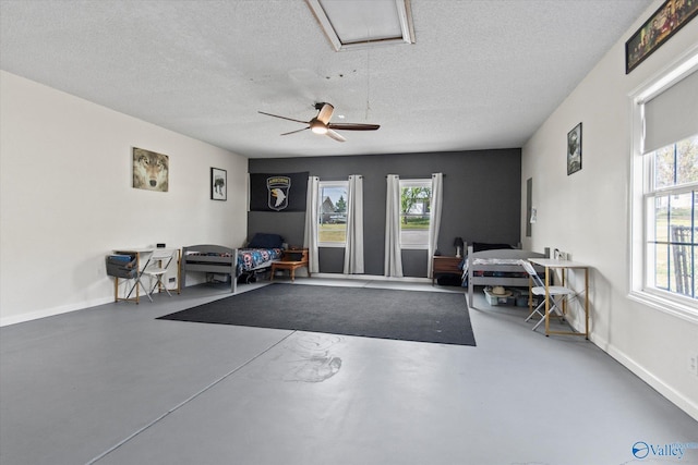 interior space featuring baseboards, a textured ceiling, ceiling fan, and attic access