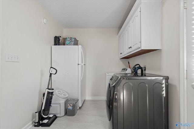 washroom featuring independent washer and dryer, cabinet space, and baseboards