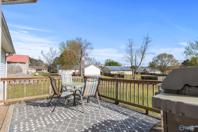 wooden terrace with a residential view, outdoor dining area, fence, and a yard