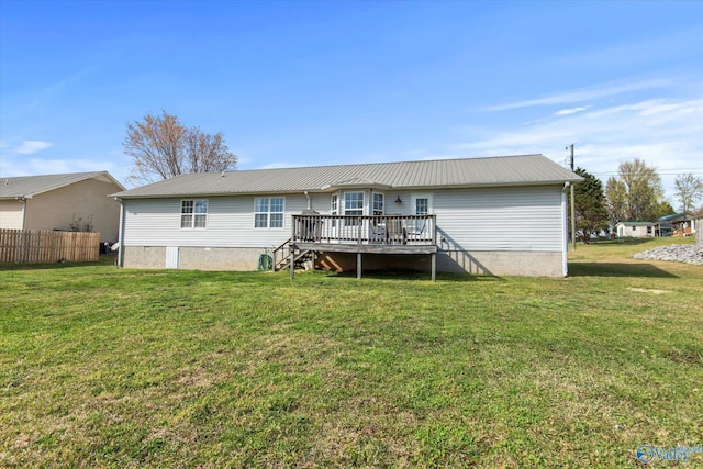 back of property with a wooden deck, fence, a yard, and metal roof