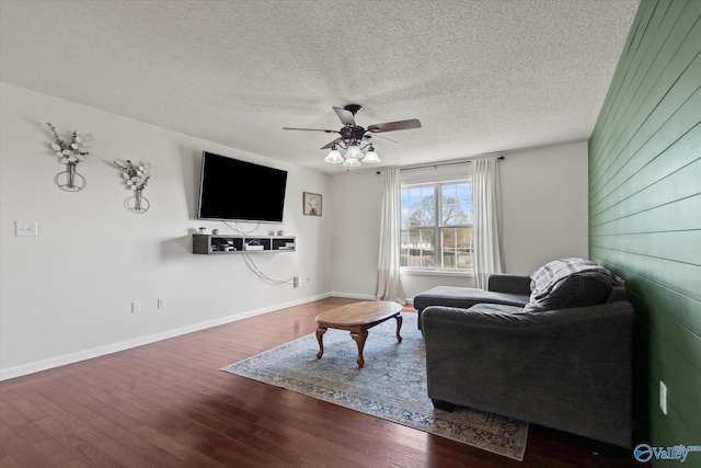 living area featuring hardwood / wood-style floors, a ceiling fan, baseboards, and a textured ceiling
