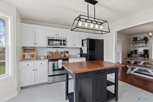 kitchen featuring white cabinetry, decorative light fixtures, backsplash, and appliances with stainless steel finishes