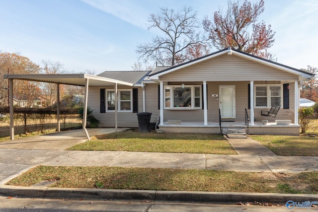 view of front of property with an attached carport, a front yard, covered porch, concrete driveway, and metal roof