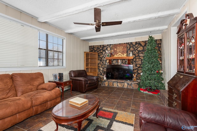 living area featuring beam ceiling, a fireplace, a textured ceiling, and a ceiling fan