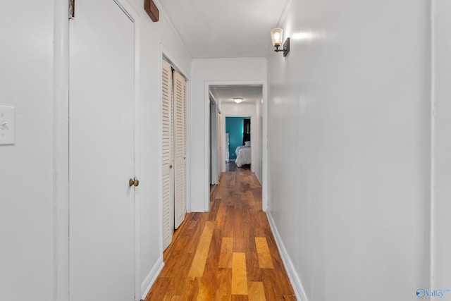 corridor featuring light wood finished floors and baseboards