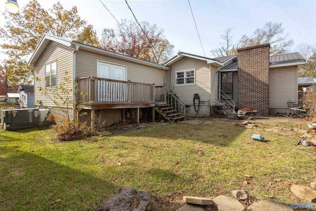 back of property featuring a deck, a yard, entry steps, and metal roof