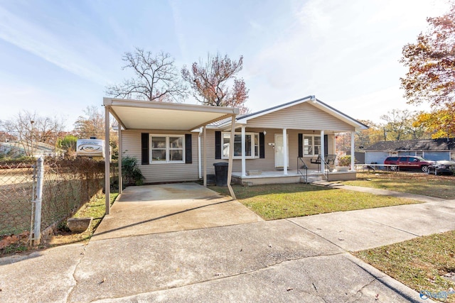 ranch-style house with concrete driveway, fence, covered porch, and a front yard