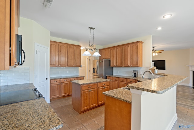 kitchen featuring a peninsula, stainless steel refrigerator with ice dispenser, tasteful backsplash, and black microwave