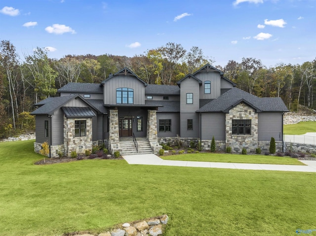 view of front of home featuring stone siding, a front lawn, board and batten siding, and roof with shingles