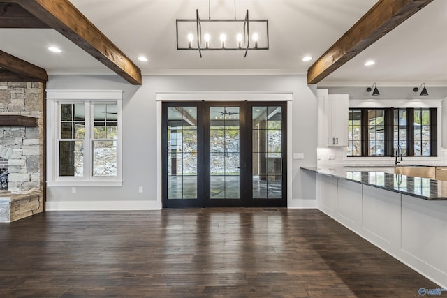 interior space with a wealth of natural light, dark wood-type flooring, and beamed ceiling