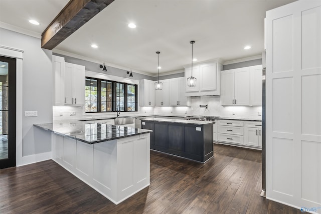 kitchen with a peninsula, dark wood-style flooring, a sink, white cabinetry, and dark stone counters