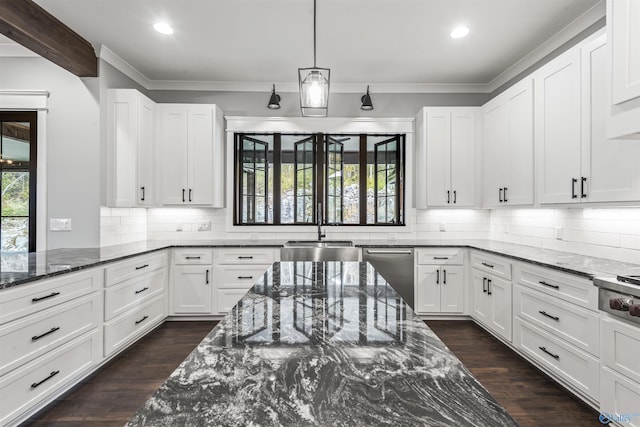 kitchen with appliances with stainless steel finishes, dark stone countertops, a sink, and white cabinetry