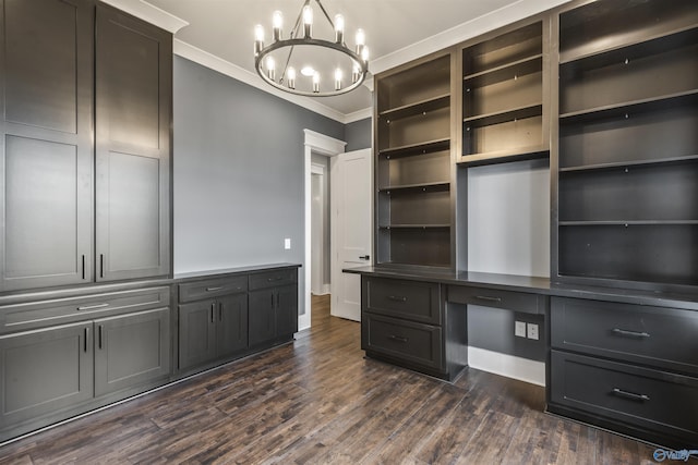 unfurnished office featuring a chandelier, baseboards, ornamental molding, dark wood-style floors, and built in desk