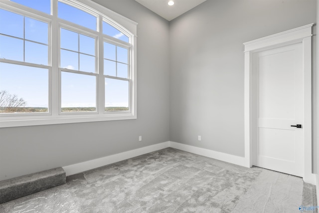 spare room featuring light carpet, recessed lighting, and baseboards