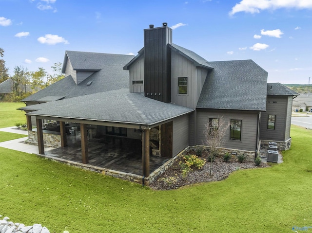 rear view of property featuring a patio area, a shingled roof, and a lawn