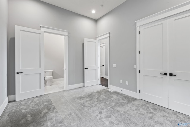 unfurnished bedroom with recessed lighting, a closet, light colored carpet, connected bathroom, and baseboards