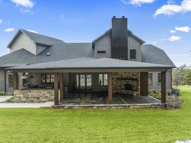 back of property with roof with shingles, a chimney, a lawn, a patio area, and a bar