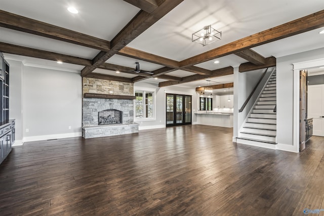 unfurnished living room with beam ceiling, dark wood finished floors, a fireplace, stairway, and baseboards