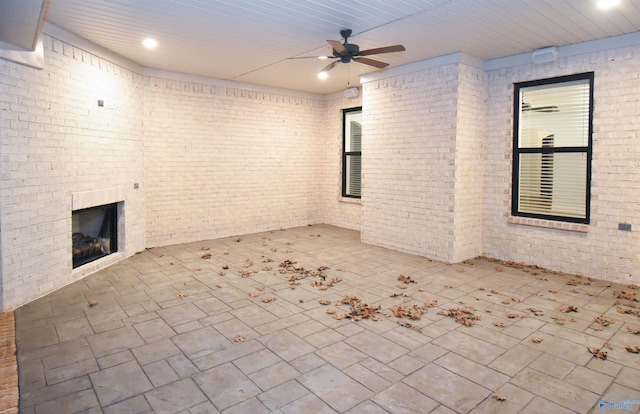 unfurnished living room with brick wall, a fireplace, wood ceiling, and ceiling fan