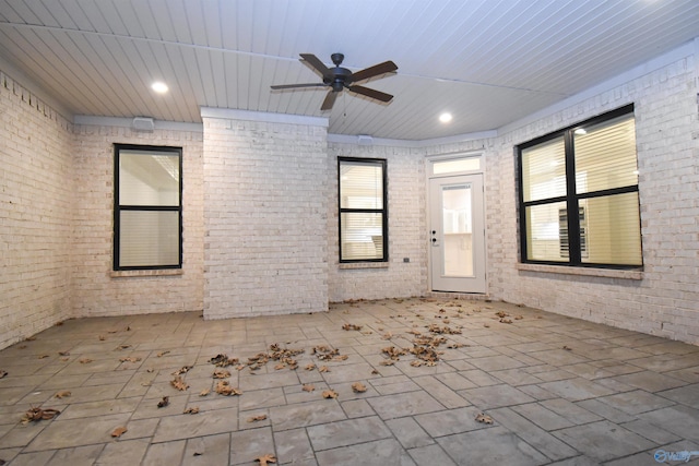 spare room with brick wall, wood ceiling, plenty of natural light, and ceiling fan