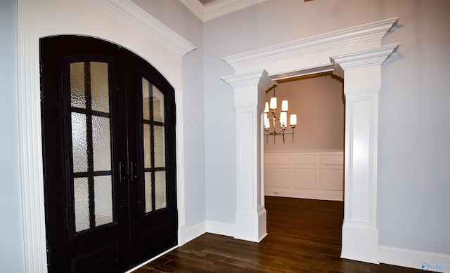 foyer entrance featuring dark wood-type flooring, an inviting chandelier, ornamental molding, french doors, and ornate columns