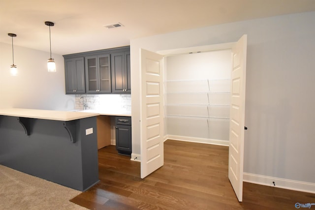 kitchen with kitchen peninsula, a kitchen breakfast bar, backsplash, decorative light fixtures, and dark hardwood / wood-style flooring