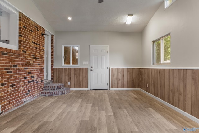 2703 Oakdale Ter, Huntsville, AL 35810 - empty room featuring wainscoting, wood finished floors, brick wall, wood walls, and a textured ceiling