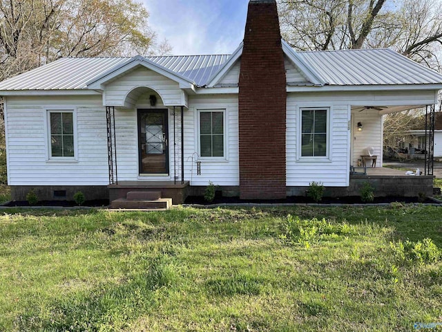 view of front of property with metal roof, a front lawn, a chimney, and a ceiling fan