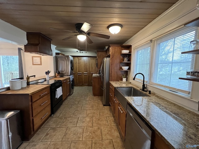 kitchen with sink, stacked washer and dryer, light stone counters, stainless steel appliances, and wooden ceiling