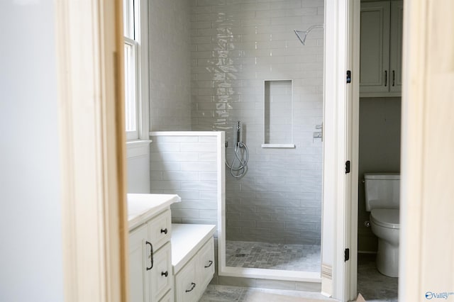 bathroom with tile patterned floors, vanity, toilet, and a tile shower