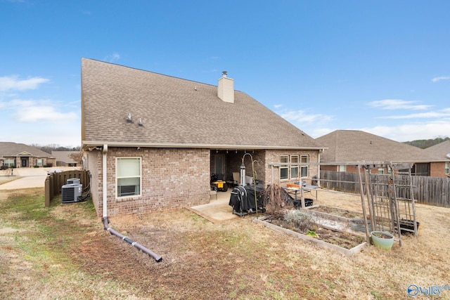 rear view of house featuring brick siding, a chimney, a shingled roof, central AC, and a patio area