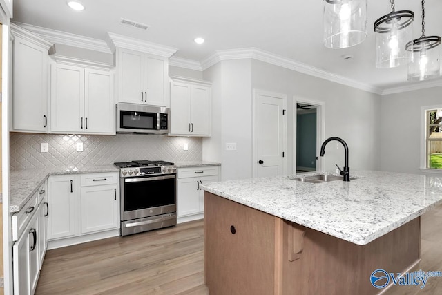 kitchen with sink, appliances with stainless steel finishes, a kitchen island with sink, decorative backsplash, and white cabinets