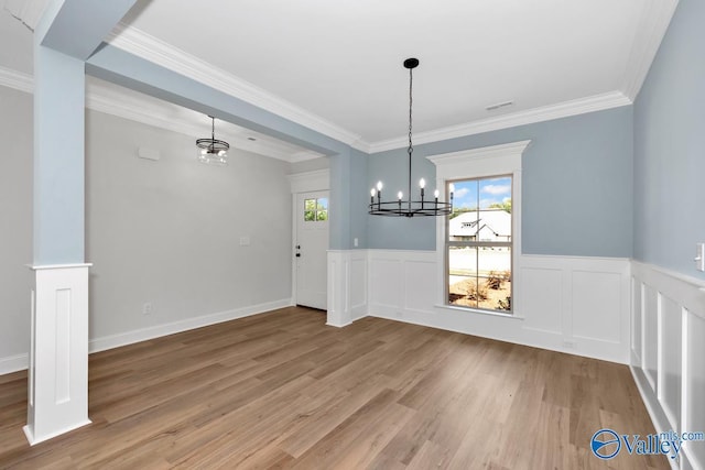 unfurnished dining area with a notable chandelier, wood-type flooring, and ornamental molding