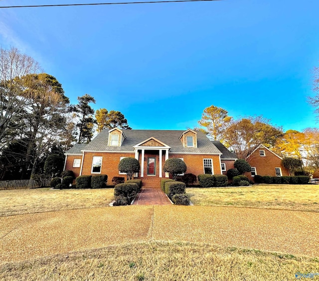 view of front of property with brick siding, fence, and a front lawn