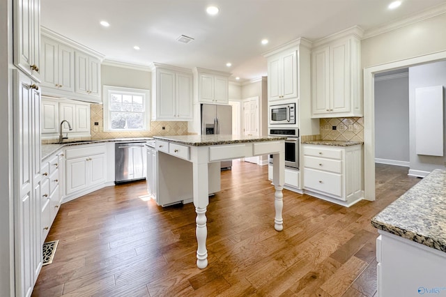 kitchen featuring stainless steel appliances, a kitchen island, and white cabinets