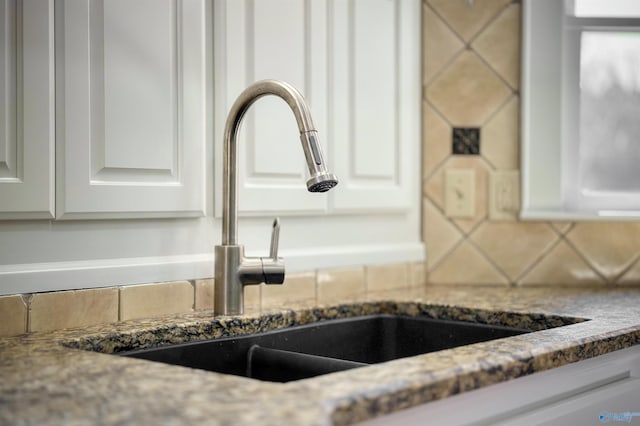 details featuring tasteful backsplash, stone counters, a sink, and white cabinetry