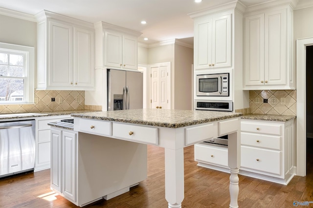 kitchen with light stone countertops, a kitchen island, appliances with stainless steel finishes, and white cabinets