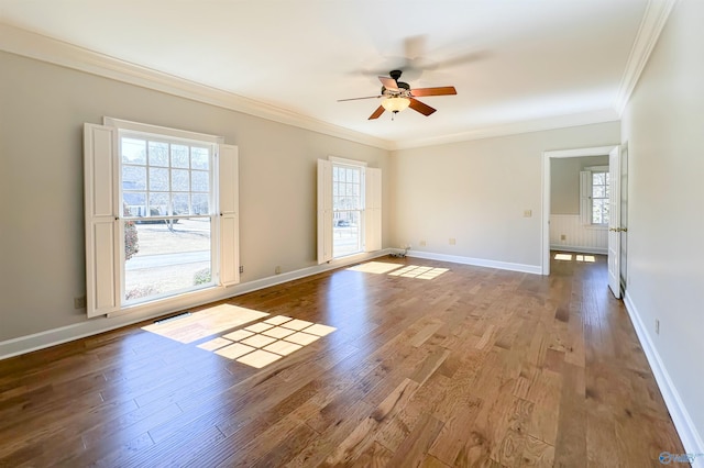 spare room with baseboards, wood finished floors, a ceiling fan, and crown molding