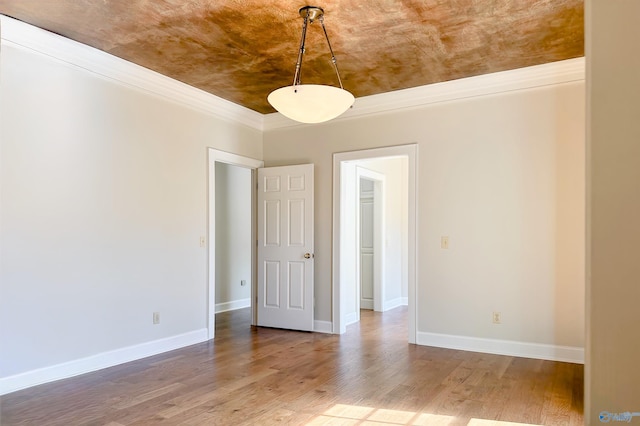 unfurnished room featuring crown molding, wood finished floors, and baseboards