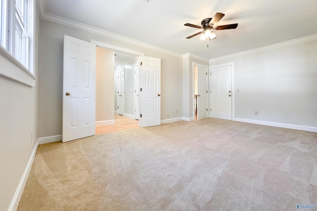 unfurnished bedroom featuring ornamental molding, light colored carpet, baseboards, and a ceiling fan