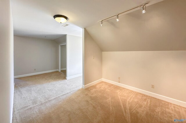 additional living space featuring visible vents, baseboards, vaulted ceiling, and light colored carpet