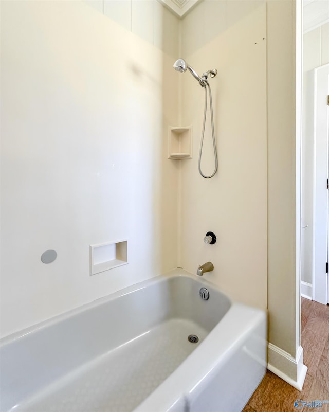 bathroom with baseboards, tub / shower combination, and wood finished floors