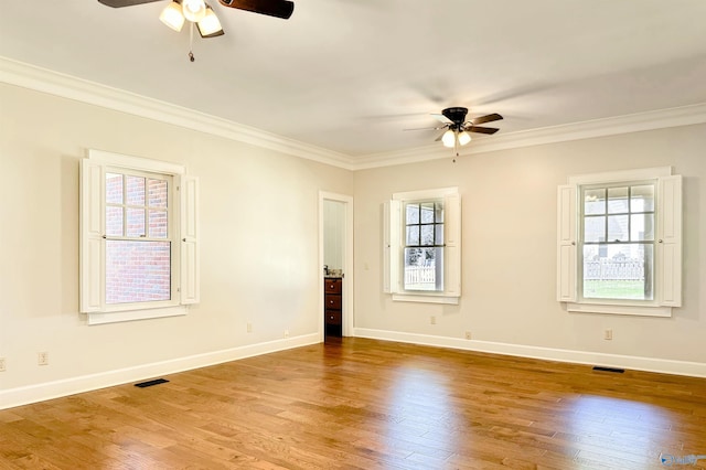 empty room featuring crown molding, baseboards, and wood finished floors