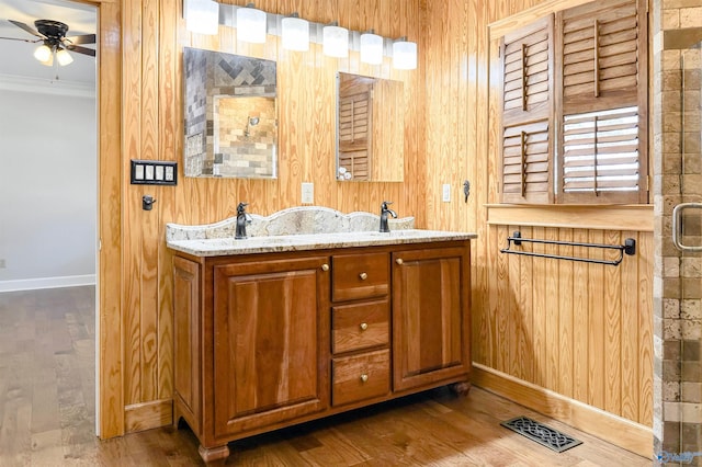 bathroom featuring double vanity, visible vents, ceiling fan, wood finished floors, and crown molding