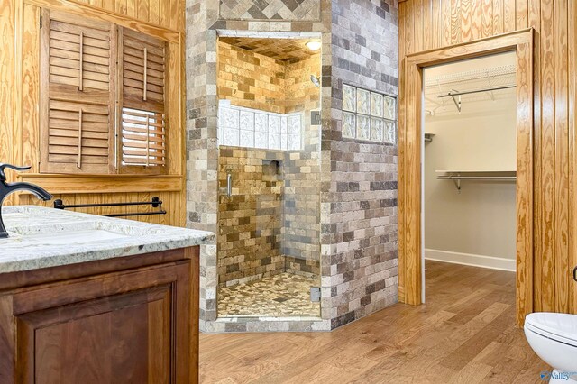 full bathroom featuring a spacious closet, toilet, a stall shower, vanity, and wood finished floors