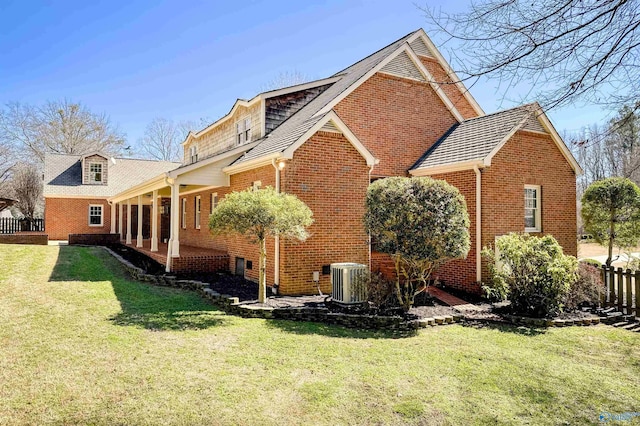 view of side of property with a yard, central AC unit, and brick siding