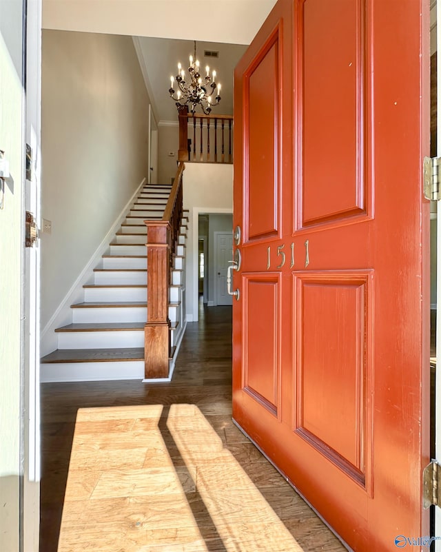 entryway with dark wood-style floors, stairs, visible vents, and an inviting chandelier