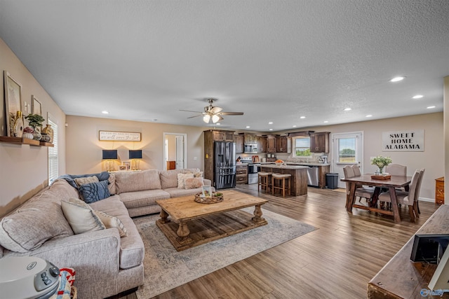 living area featuring recessed lighting, a textured ceiling, a ceiling fan, and wood finished floors